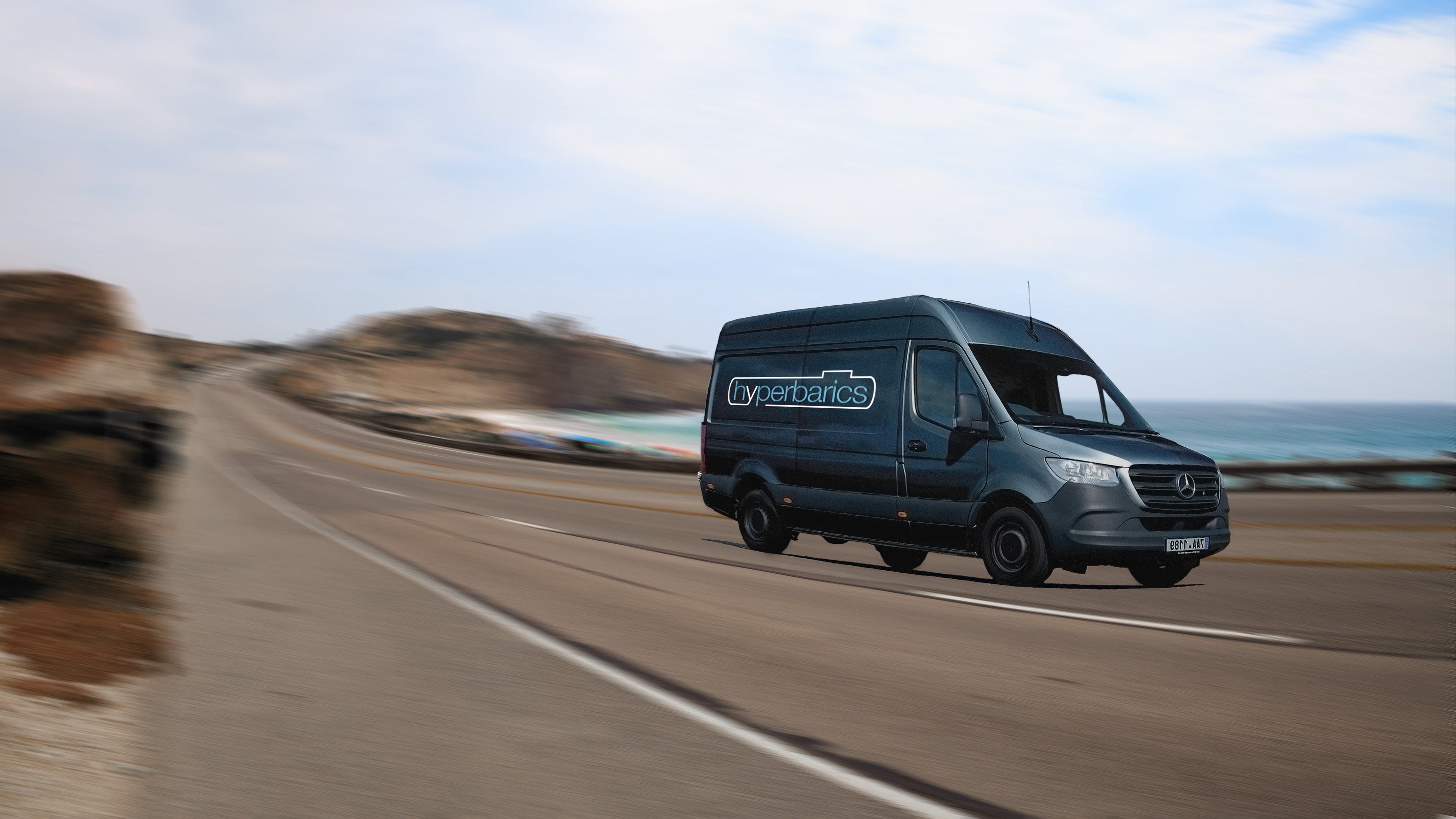 Black "Hyperbarics" mobile hyperbaric oxygen therapy van driving on a coastal road with a scenic background